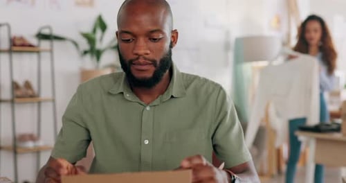 Man Seals Cardboard Box for Shipping in Office