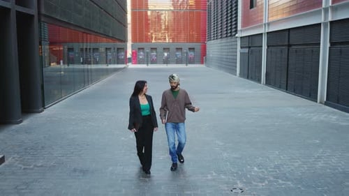 Cooperative businesspeople walking on city sidewalk and talking about latest projects