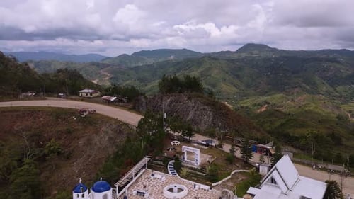 Aerial Drone View of Curving Mountain Road on Steep Ridge Overlooking Green Valley