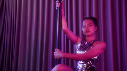Female Dancer Warning Up on Pole in Neon Studio