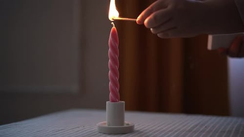 Closeup Hands of Unrecognizable Woman Lighting Handmade Scented Candle with Match in Room with Dark