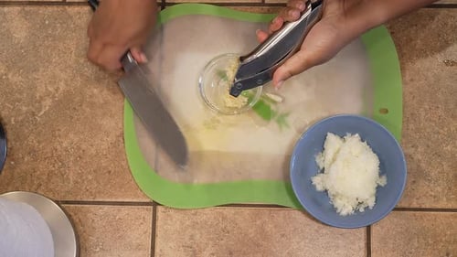 Mincing organic garlic in a press for use in a homemade vegan recipe - overhead view WILD RICE SERIE