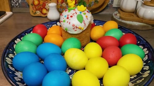 Multi-colored Easter chicken eggs on a platter with Easter cake
