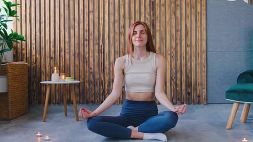 A Woman Sits Peacefully and Contentedly in a Tranquil Setting Surrounded By Flickering Candles That