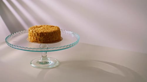 Freshly prepared delicious Napoleon cake from puff pastry on a transparent stand on a white