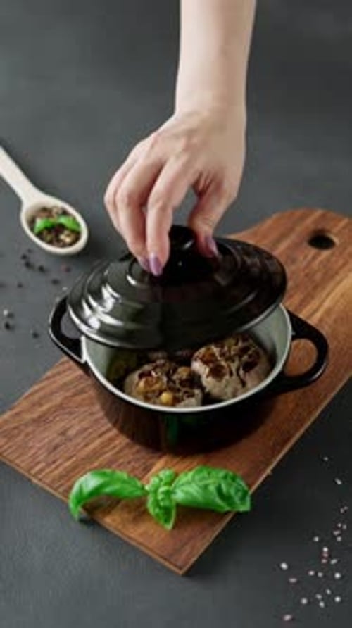 Garlic bulbs Baked with olive oil and spices in black dish. Black background