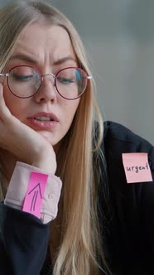 Retrato de una mujer de negocios caucásica frustrada en la oficina con pegatinas, muchas tareas, notas adhesivas