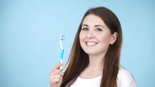 Woman Smiling and Brushing Teeth with a Toothbrush