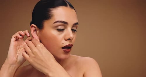 Face, woman and earring with makeup in studio for beauty, cosmetics transformation and makeover