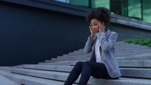 Stressed Woman Sitting on Steps Outside Building