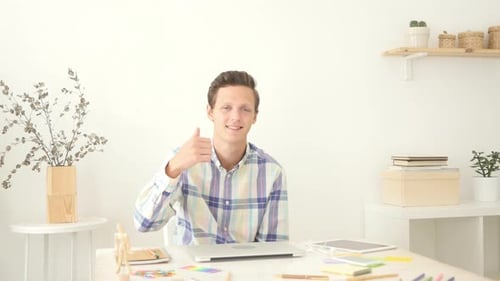 Young Adult Gives Thumbs Up at Desk