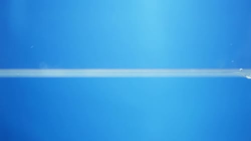 Slow-motion water drop hits a reflective surface, rippling outward with perfect clarity and showing