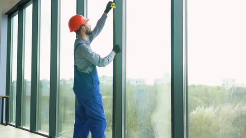 A Repairman in Uniform Installs Pvc Windows in New Office