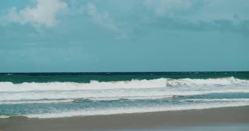 The picturesque sight of a tropical beach, featuring gentle waves and a backdrop of vivid blue skies