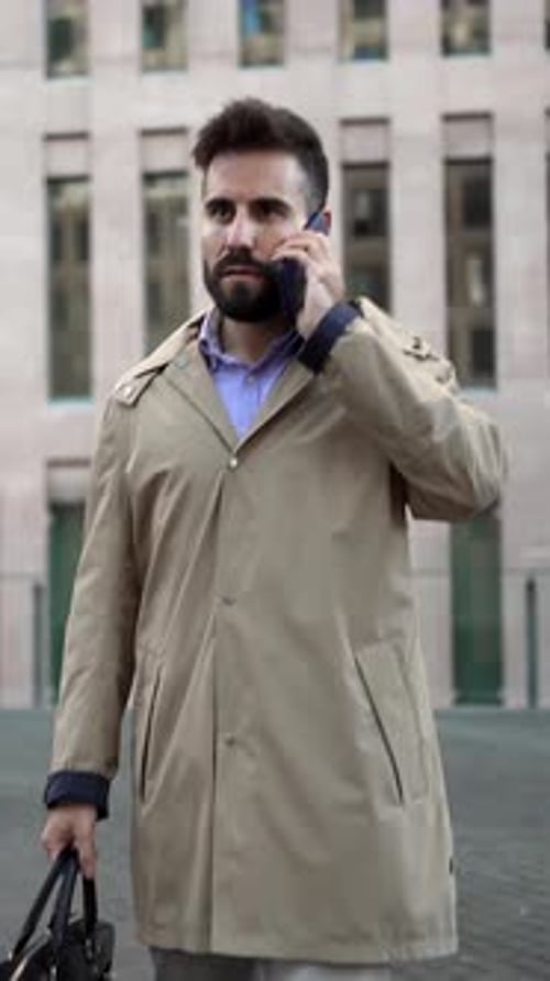 Serious Businessman Walking Down the Street on a Phone Call Carrying Professional Briefcase