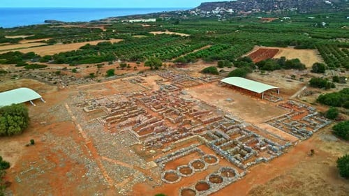 Ancient ruins of a Greek palace near the sea with distant hills and green fields