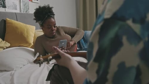Friends Relaxing Indoors with Guitar and Phone