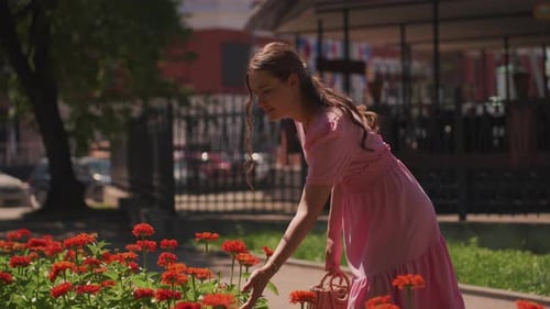 Young Woman Enjoys Smelling Flowers in Urban Garden