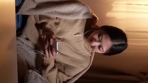 Young Woman Listening to Music Indoors at Night