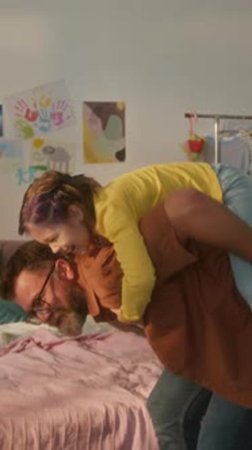 Father giving happy daughter piggyback ride in bedroom
