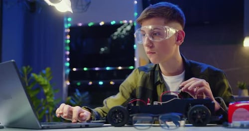 Teen Boy Assembles Toy Car with Laptop Guidance