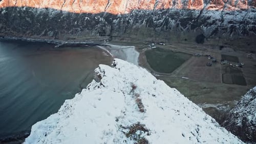 Beautiful sunrise shot from the very edge of a snow-covered mountain, looking over ocean and mountai
