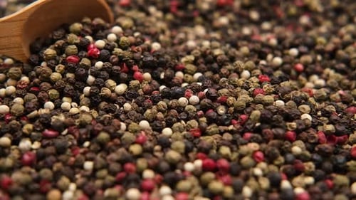 Colorful Peppercorns Scooped with a Wooden Spoon