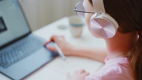 Child Using Laptop, Writing in Notebook at Home