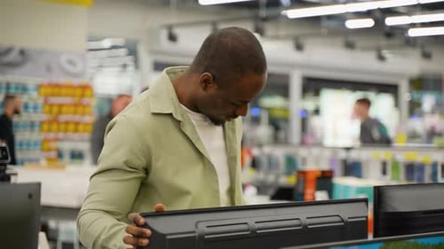 African American Customer Examining a Television in an Electronics Store with Discount