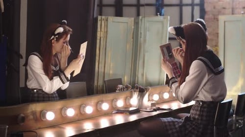 Woman Applies Eye Makeup at Lit Vanity Mirror