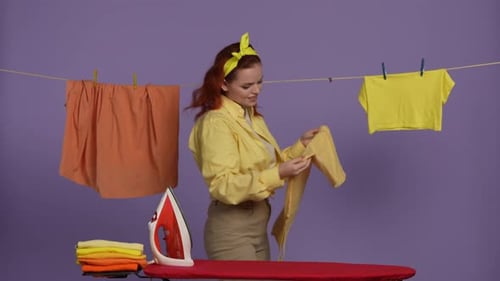 Smiling Woman Ironing Clothes in Colorful Studio