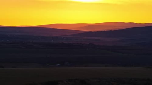 Vista aérea con un dron de las ondulantes colinas de Moldavia al anochecer, con capas de luz tenue con un amarillo brillante o
