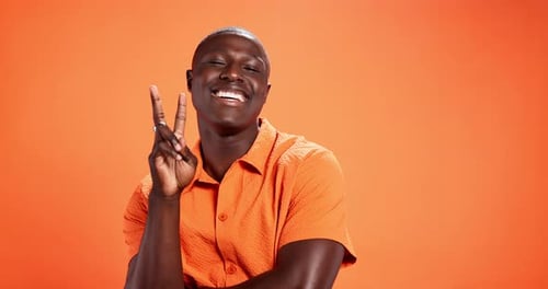 Black man, happy and face with peace sign in studio with laugh, pride or trendy style by orange