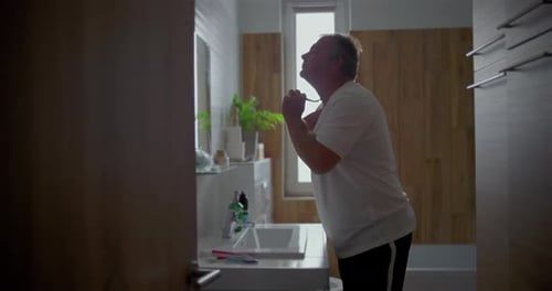 Homem se barbeando no banheiro, inclinando a cabeça para trás para um barbear suave sob o queixo, aplicado com espuma, natural