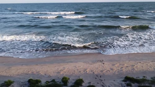 Serienaufnahme der Kamera, die rechts von einem Strand geht, und der Wellen bei Sonnenuntergang.