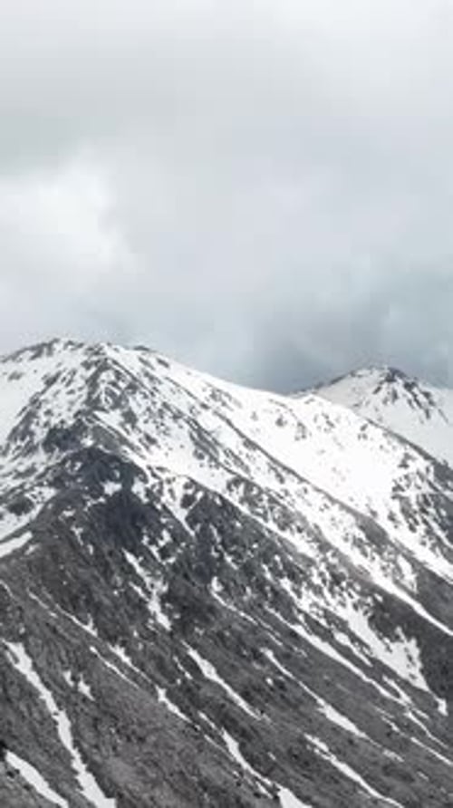 Vertical Video Winter Wonderland Aerial View of SnowBlanketed Peaks and Forest Haven