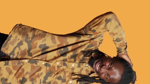 Man Lying on Side Smiling on Orange Background