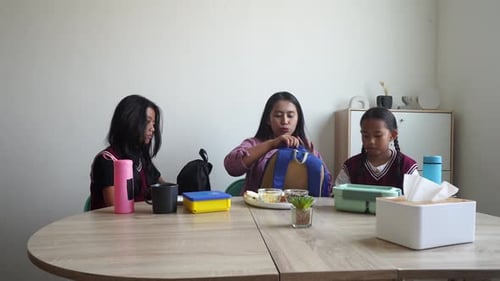 Asian Mother With Two Daughter Preparing To School With Putting Lunch Box Into Backpack