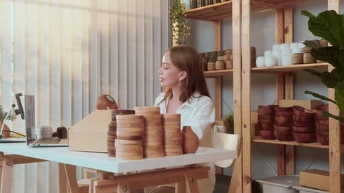A young pretty woman entrepreneur checking and packaging craft products