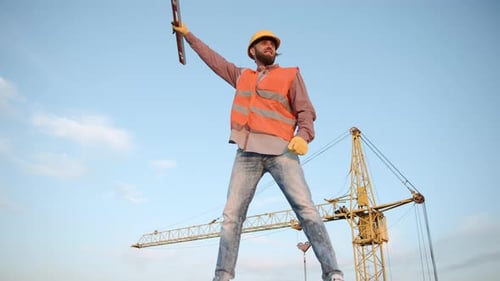 Ouvrier du bâtiment dirigeant les opérations de grue au ralenti sur un chantier pendant une journée ensoleillée