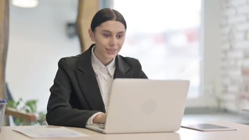 Excited Woman Celebrates Success at Laptop in Office