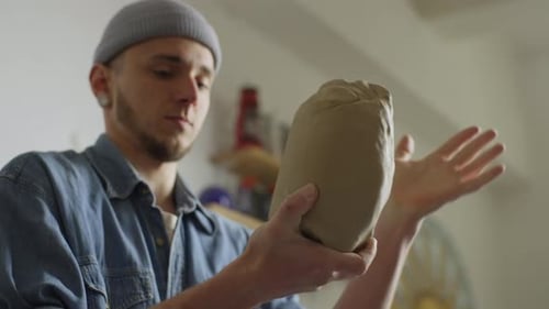 Artist Shaping Clay Sculpture in Studio