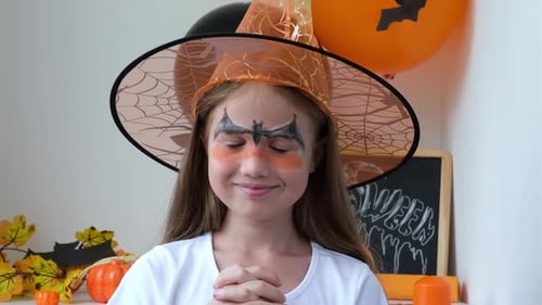 Girl Smiles Wearing Witch Hat and Halloween Makeup