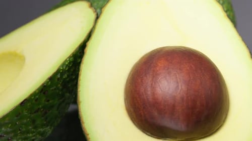 Extreme close up of ripen avocados rotating on a black background