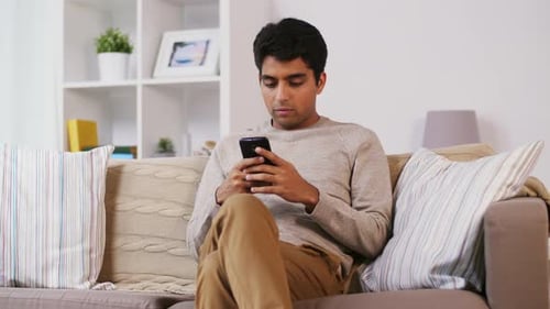 Man Relaxing on Sofa, Using Mobile Phone