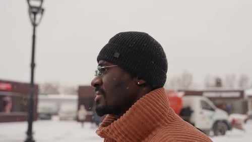Man Walking Through Snowy City Streets on Winter Day