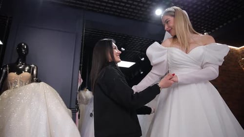 Uma noiva feliz escolhe um vestido com um vendedor em um salão de noivas