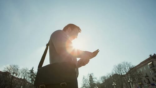 Junger hübscher, eleganter Modellmann, der ein technologisches Tablet-Gerät in der Stadt benutzt