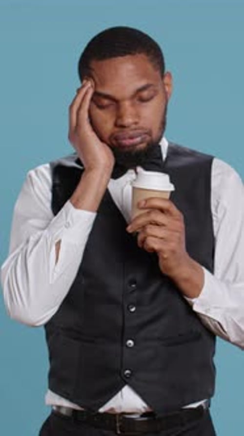 Vertical Video Unwell Hotel Porter Feeling Sick and Drinking a Cup of Coffee