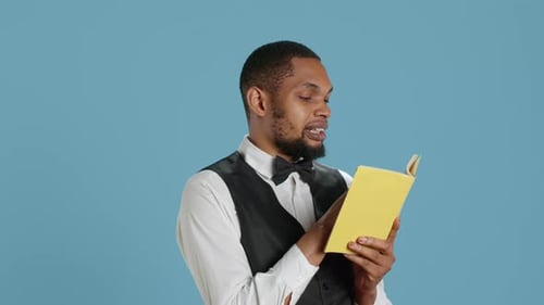Man Reading Aloud from Book with Yellow Cover